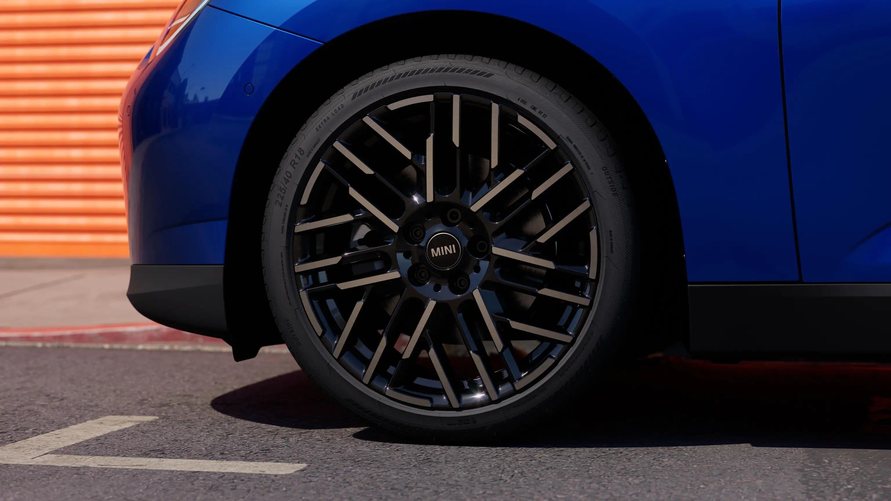 Close-up of a blue car's custom black alloy wheel with silver accents.