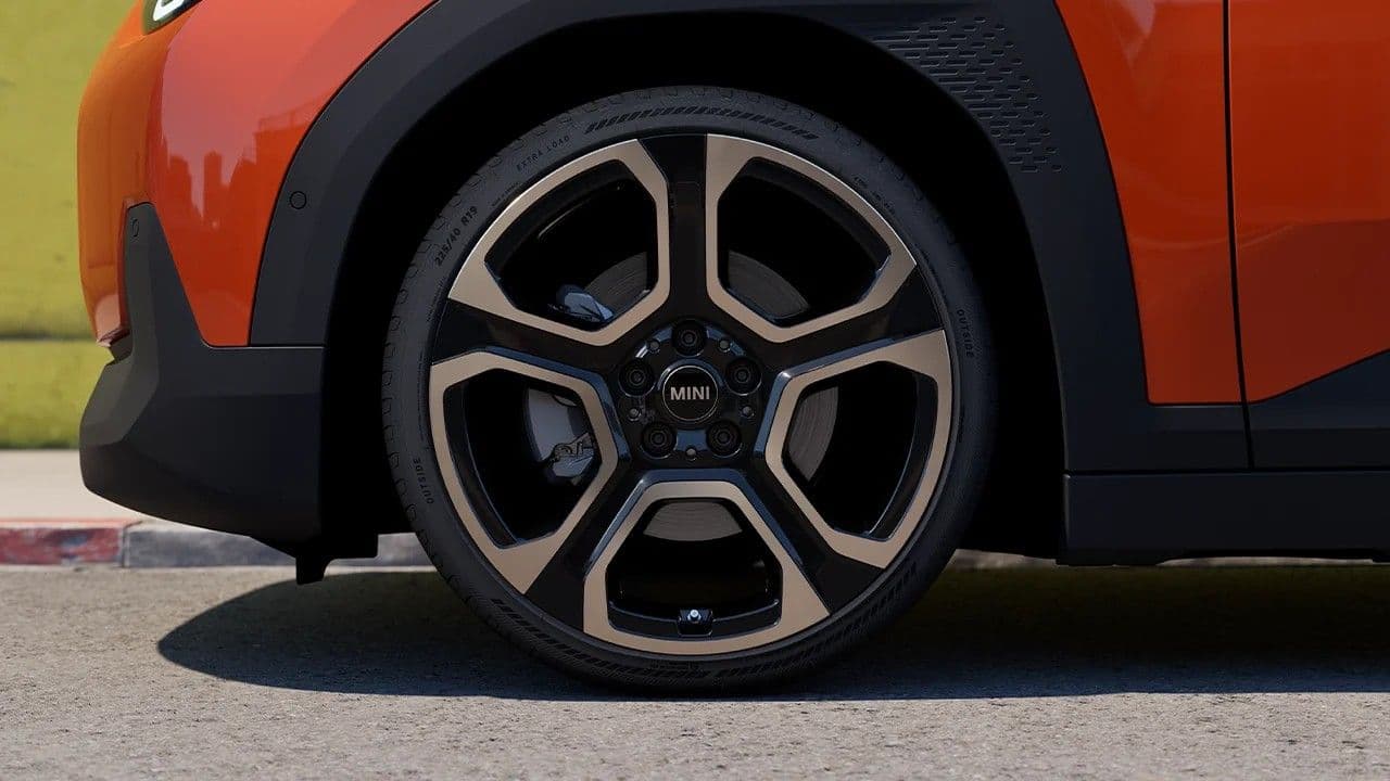 Close-up of a stylish alloy wheel with a multi-spoke design on an orange car.