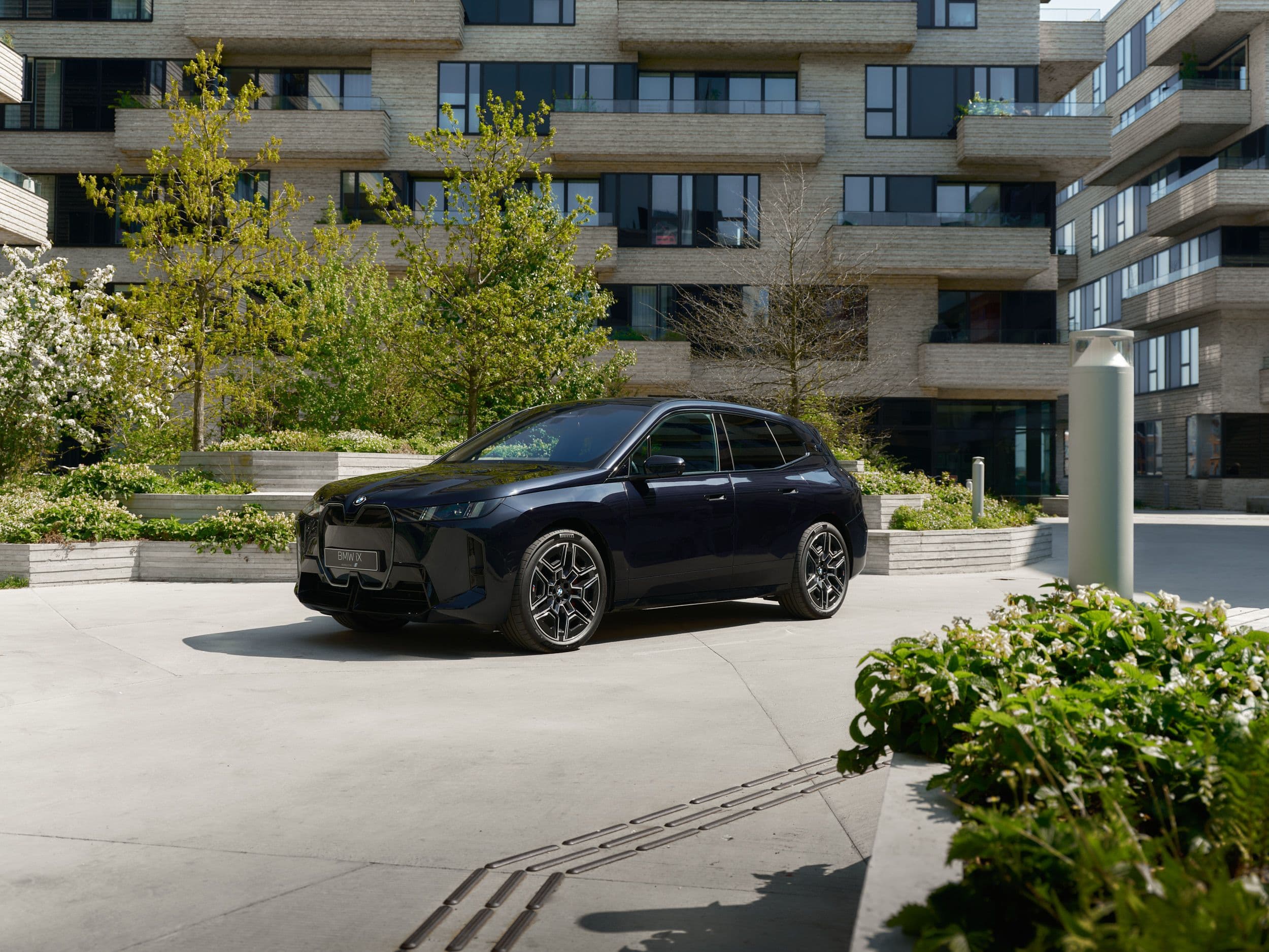 Dark blue electric BMW iX SUV parked in front of a modern building.
