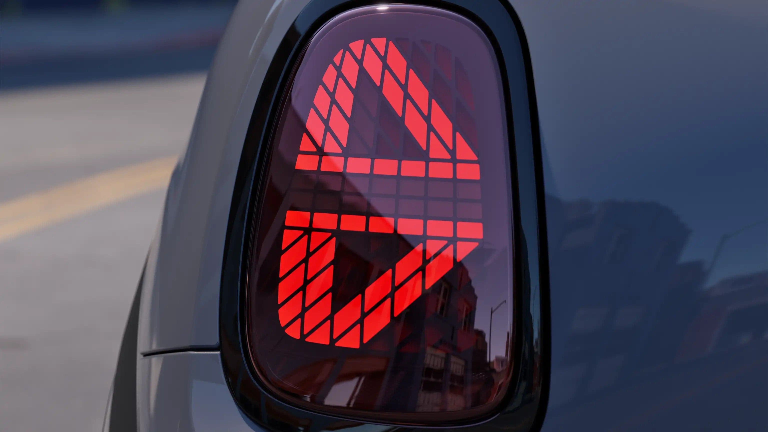 Close-up of a car's red taillight with a unique geometric design illuminated.