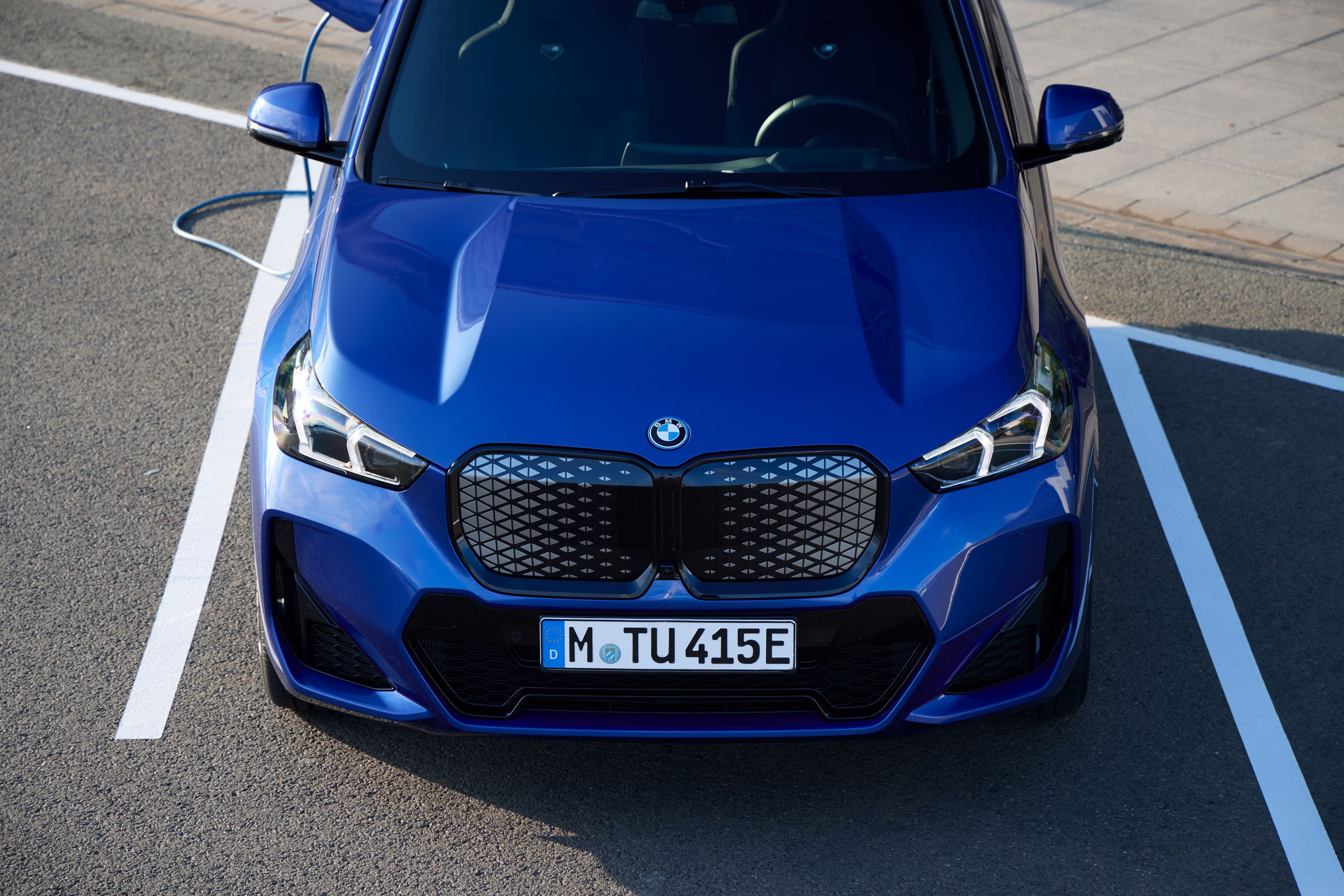 Front view of a sleek, blue BMW electric car with its signature grille and LED headlights.