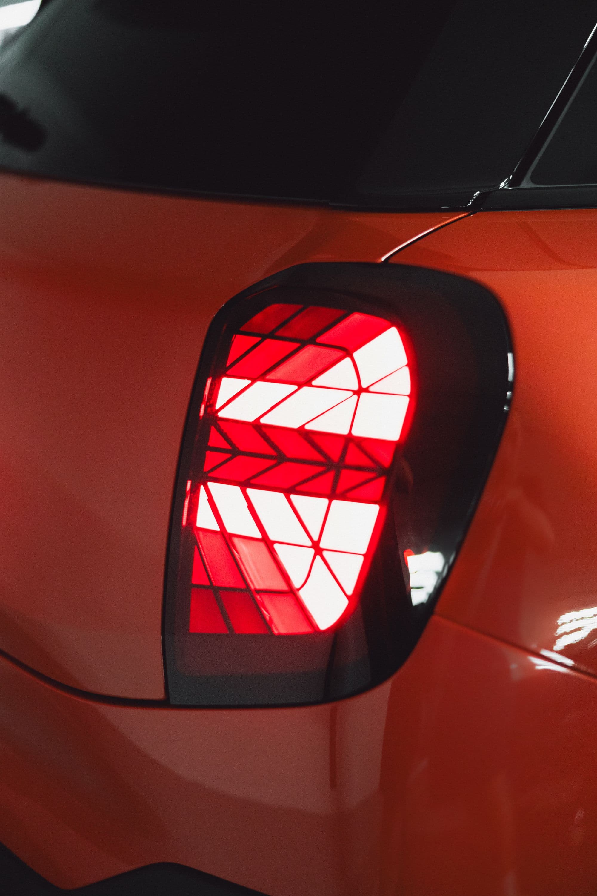 Close-up of a red car's taillight with a geometric pattern inside.