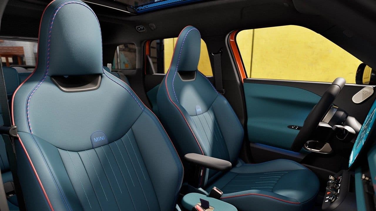 Front seats of a car with blue upholstered seats and contrasting red stitching.