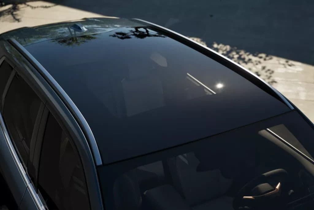 Top view of a car's panoramic sunroof reflecting sunlight on a bright day.