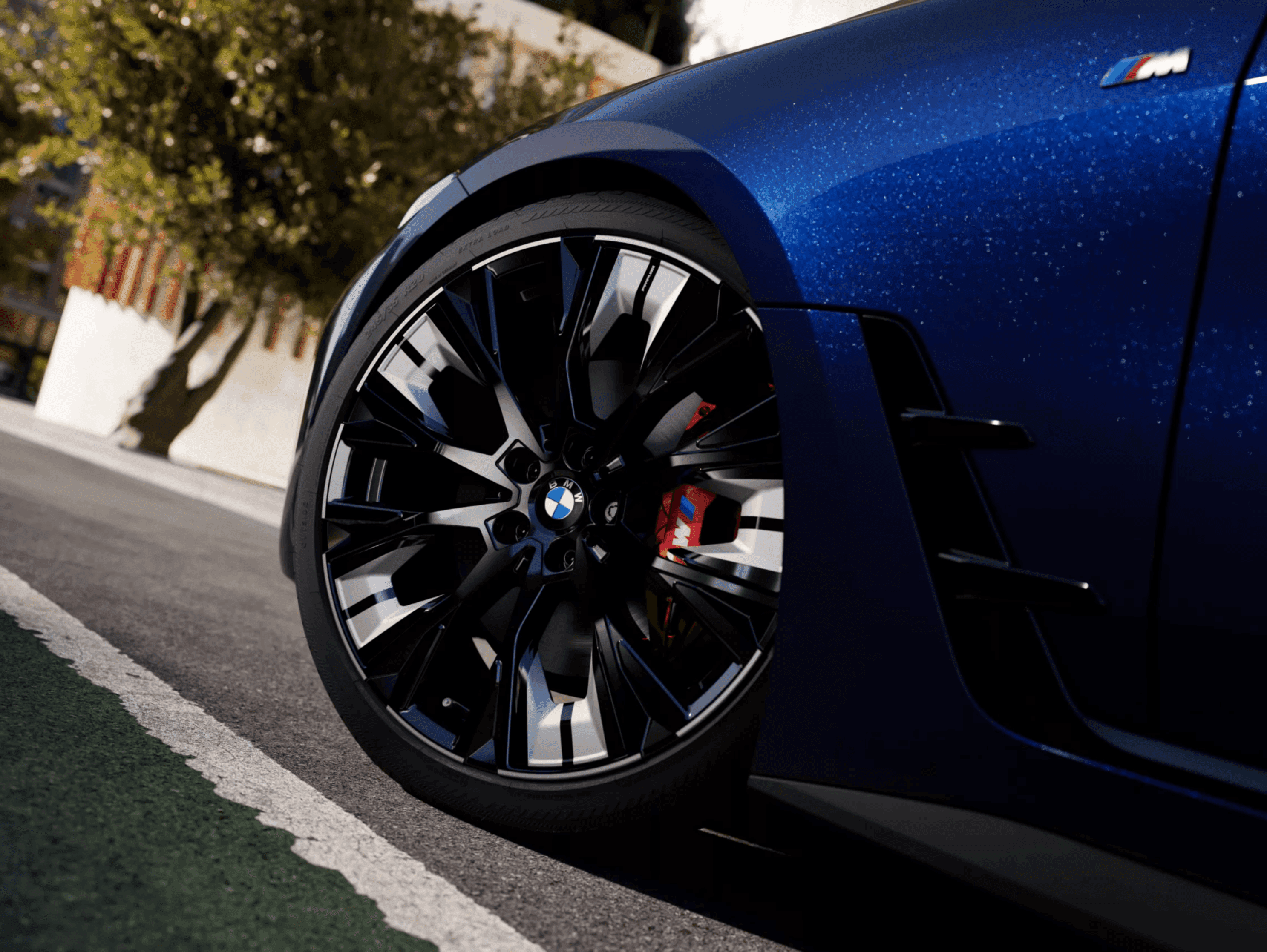 Close-up of a blue BMW M car's front wheel with black and silver rims and red brake calipers.