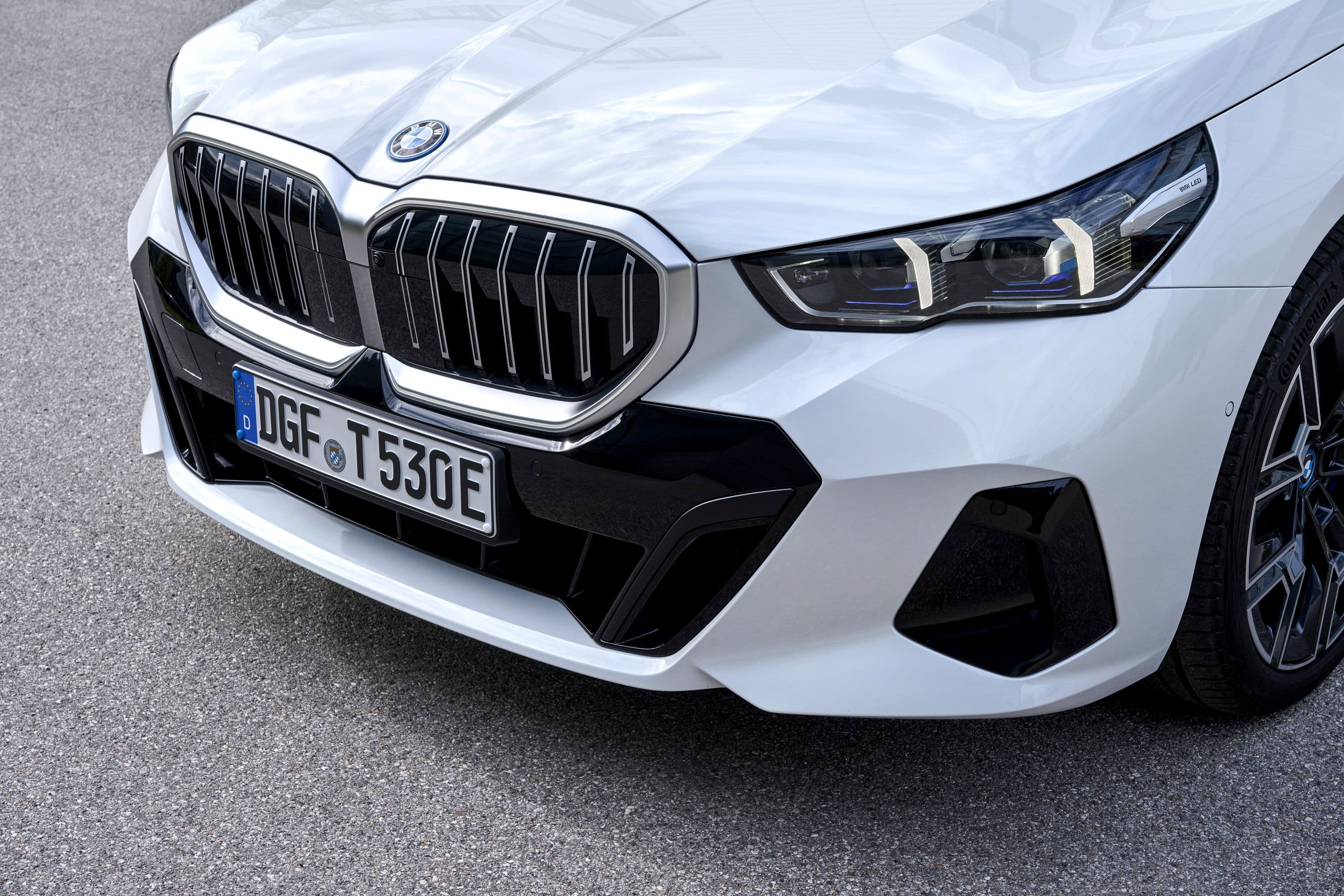 Close-up of a white BMW's front grille and headlights.