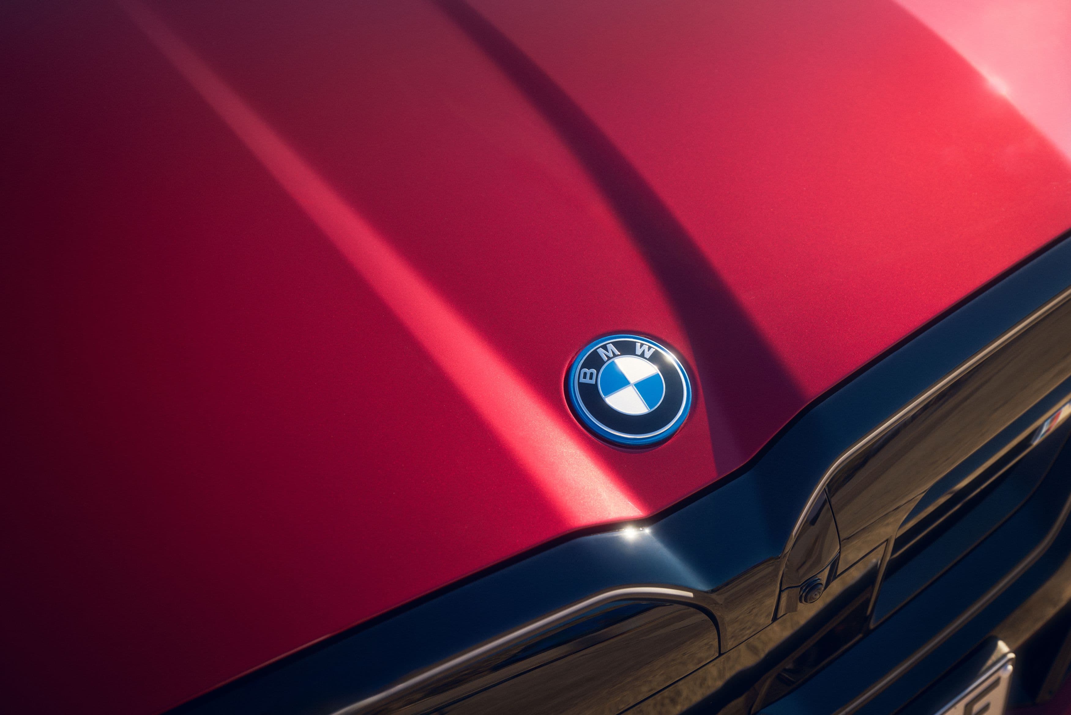 Close-up of a red BMW car hood with the iconic BMW emblem.