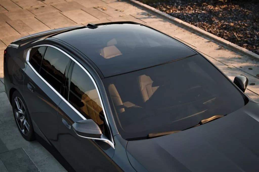 Top view of a dark grey sedan with a panoramic sunroof and tan leather interior.