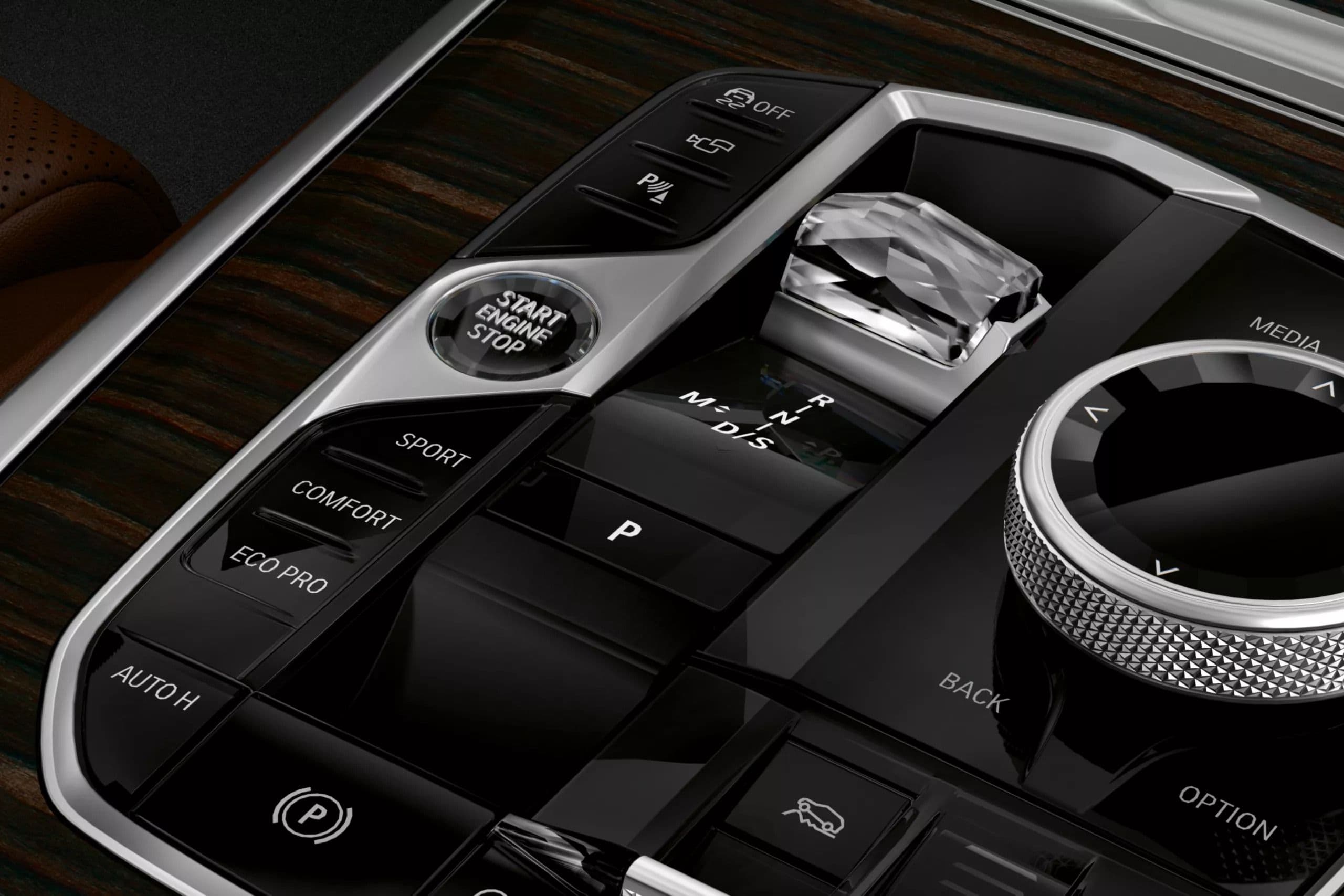 Close-up of a luxury car's dashboard featuring a start-stop button, gear selector, and drive mode controls.