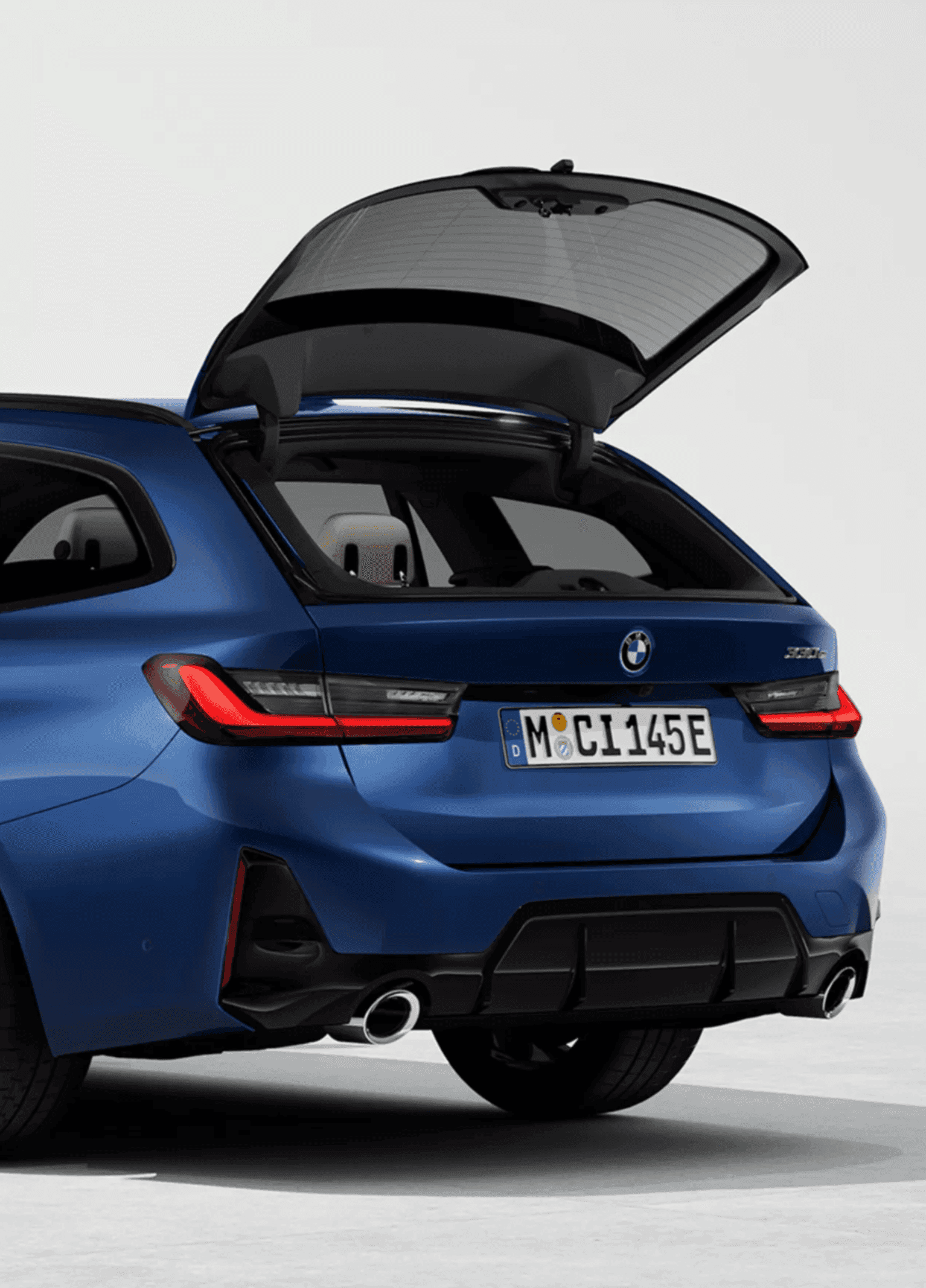 Rear view of a blue BMW touring car with its tailgate open, revealing a small plush toy inside.