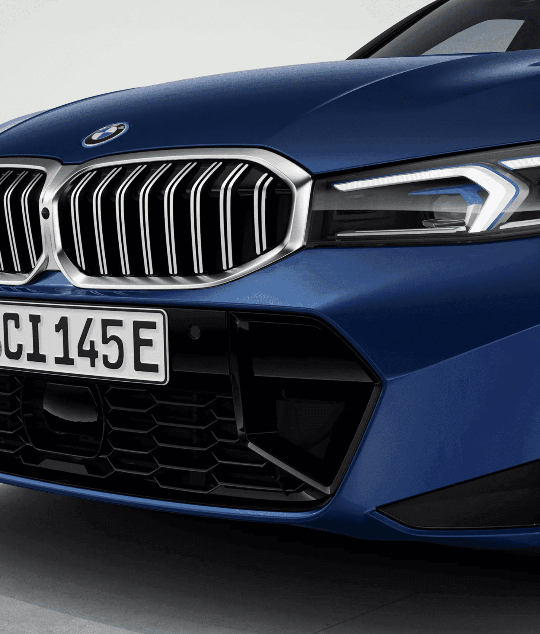 Close-up of the front grille and headlight of a dark blue BMW.
