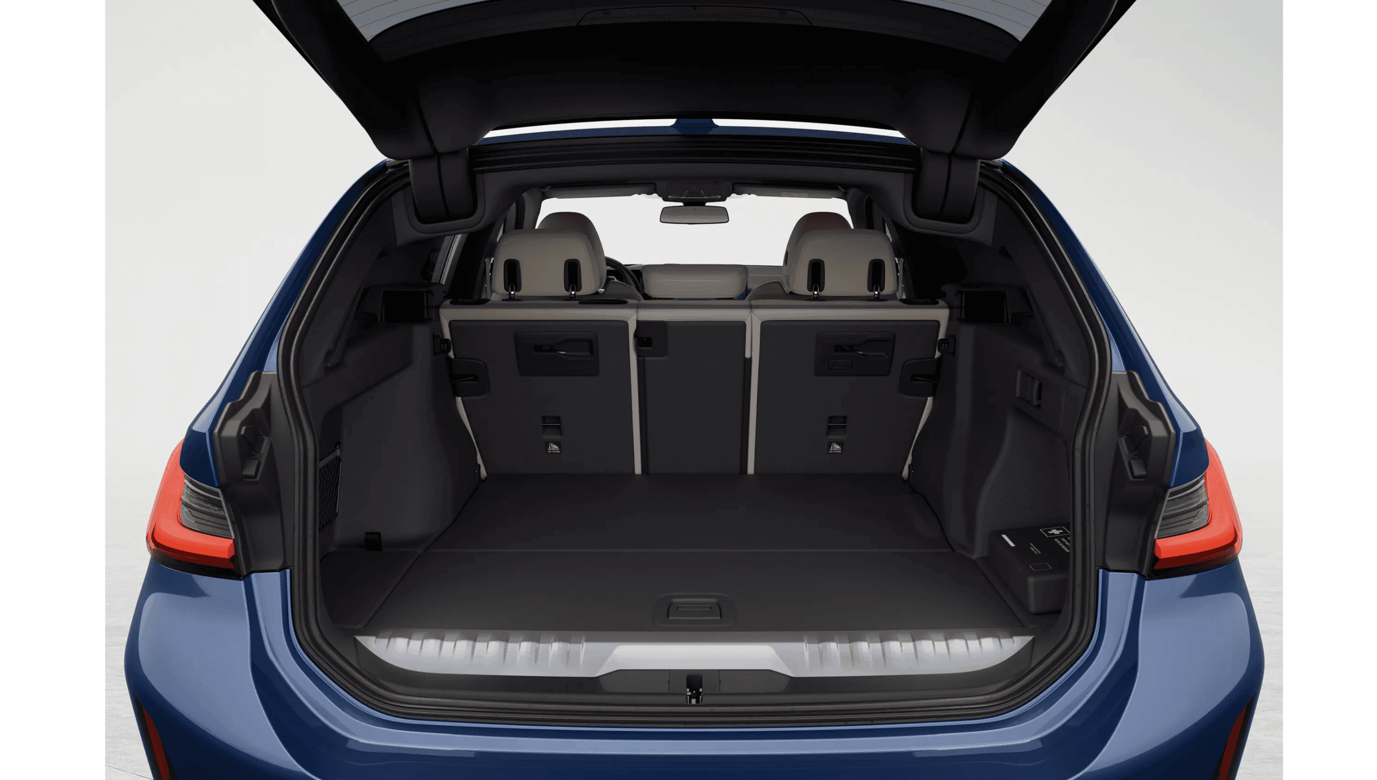The spacious, open trunk of a blue car, showing the carpeted floor and folded rear seats.