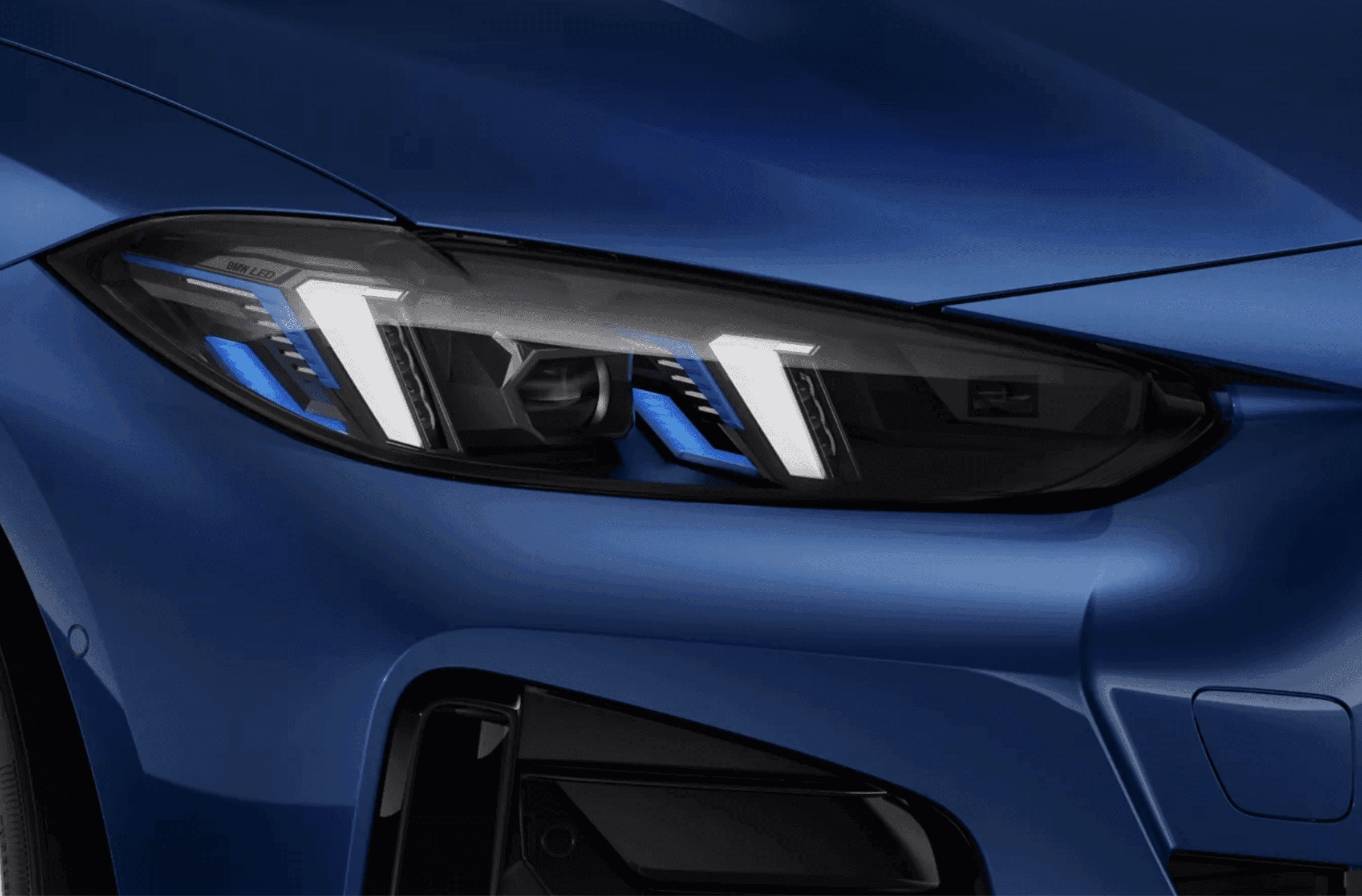 Close-up of a sleek, modern blue car's LED headlight with intricate blue accents.