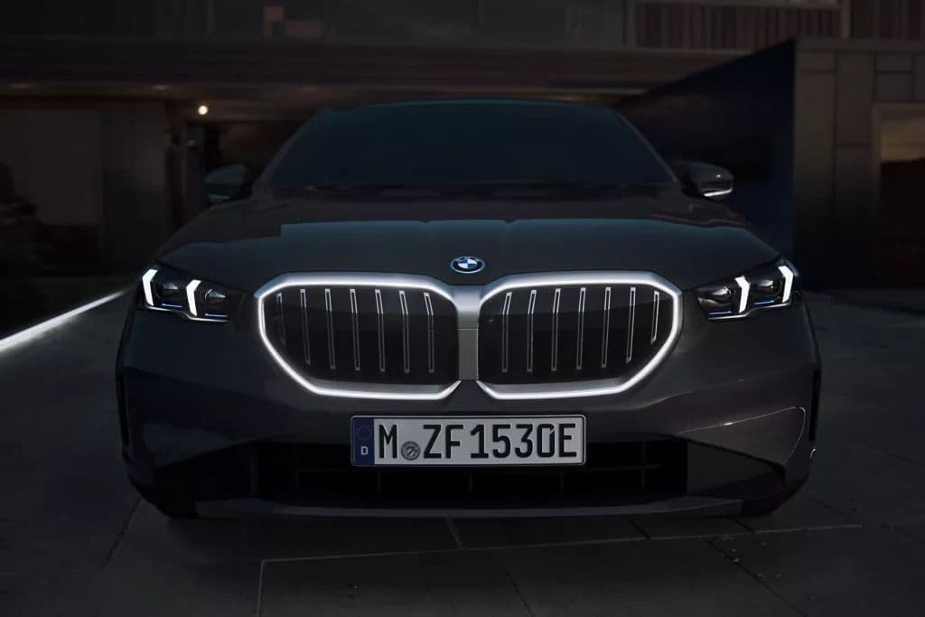 Front view of a dark BMW electric car with illuminated grille and headlights.