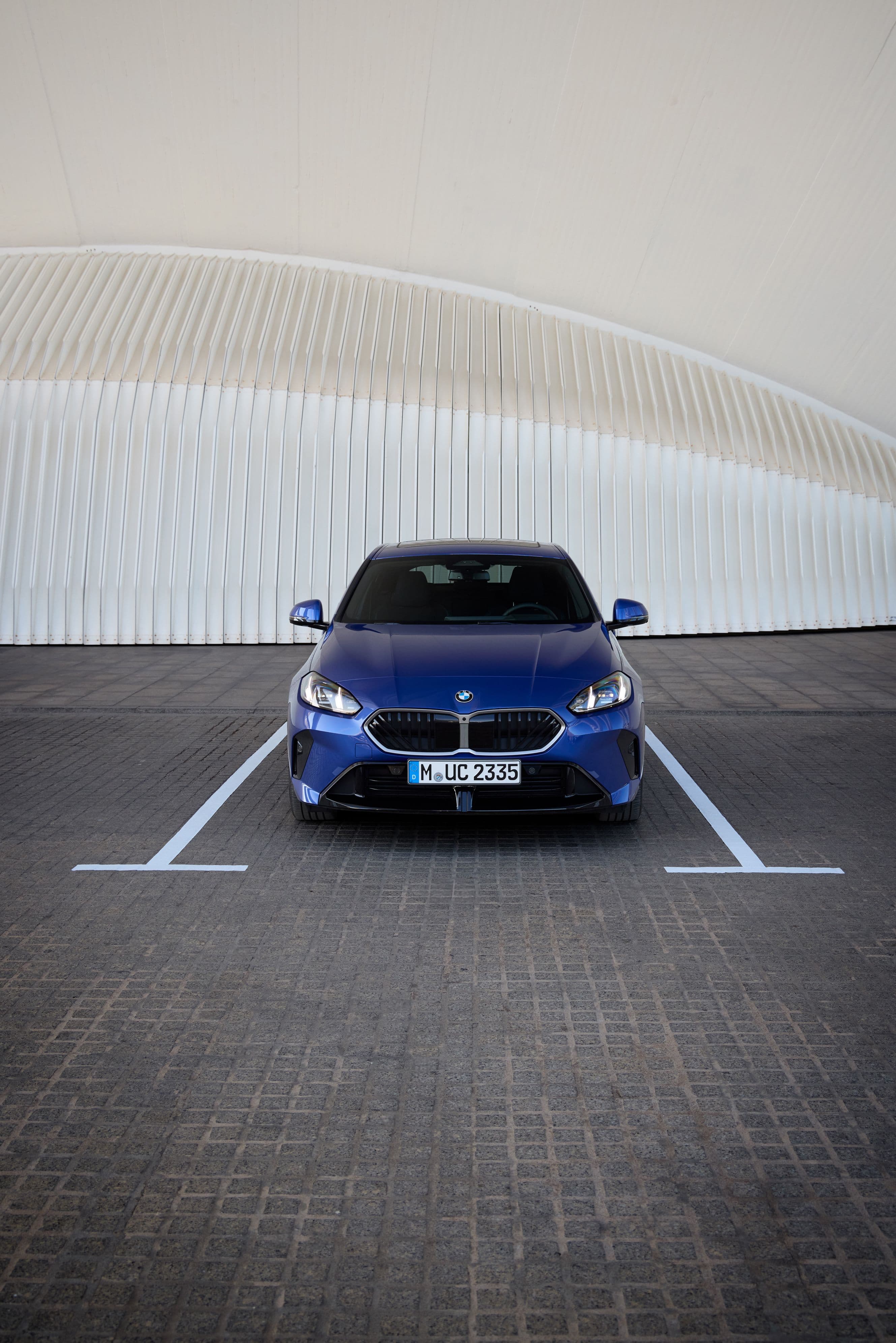 Blue BMW M2 Competition parked in a minimalist parking lot.