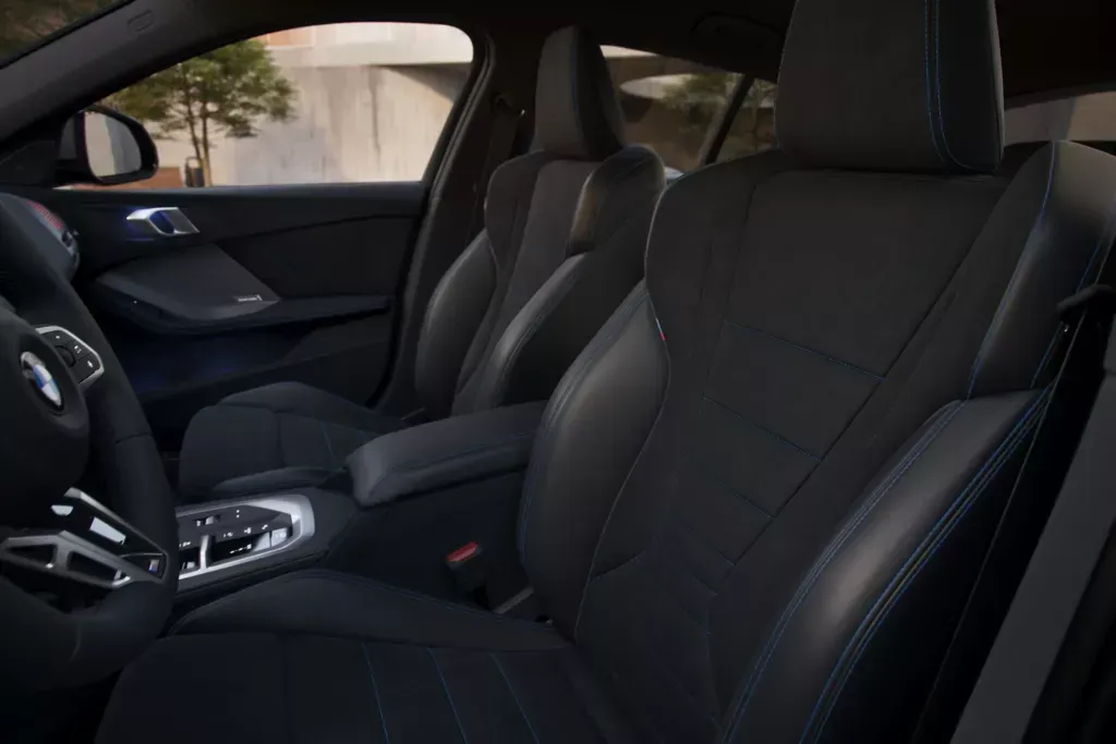 Front seats of a modern car with black leather upholstery and a central console.
