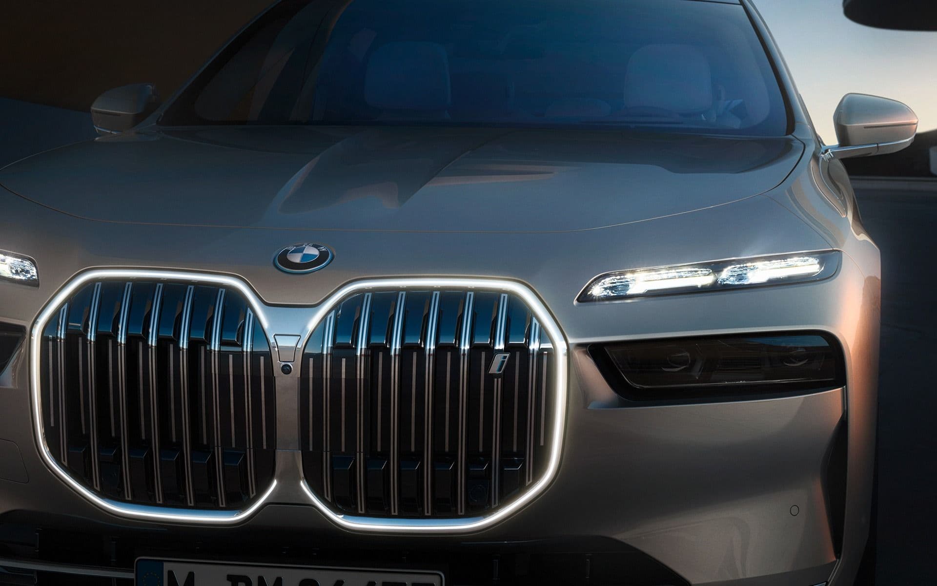 Close-up of the illuminated grille and headlights of a silver BMW.