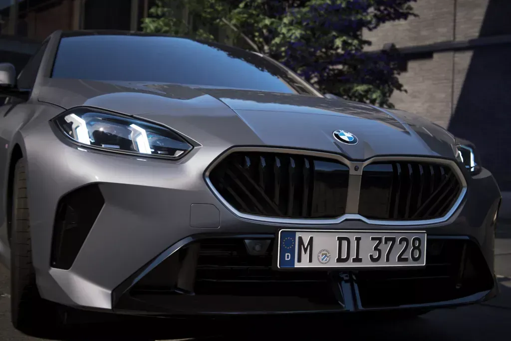 Front view of a gray BMW M sedan with its headlights illuminated and a license plate reading M DI 3728.