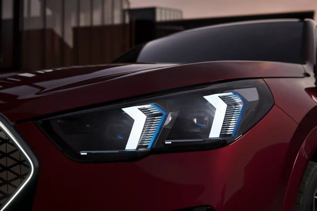 Close-up of a modern car's distinctive LED headlights with a red metallic paint finish.