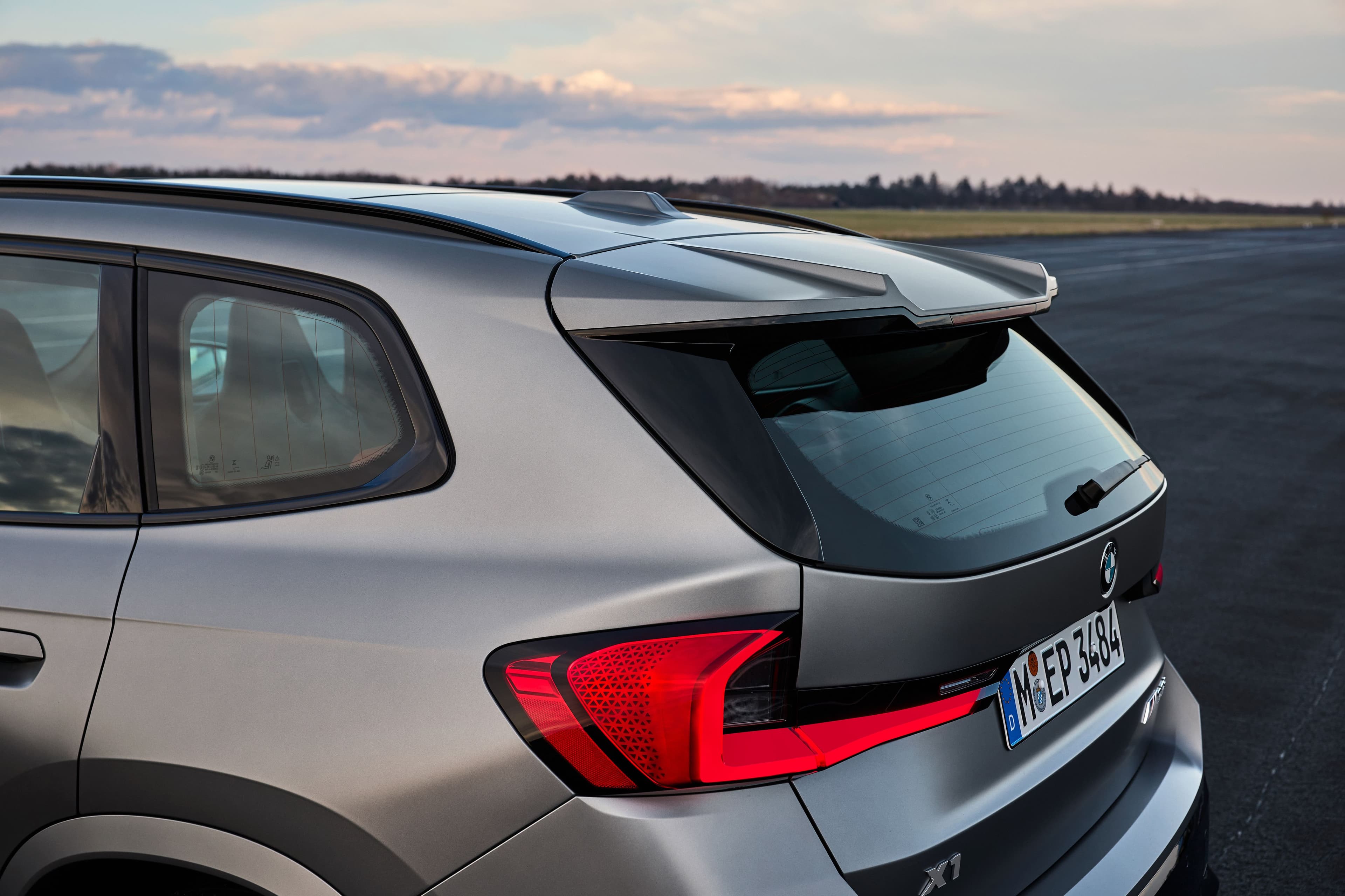 Rear view of a gray BMW X1 with a spoiler and distinctive taillight design.