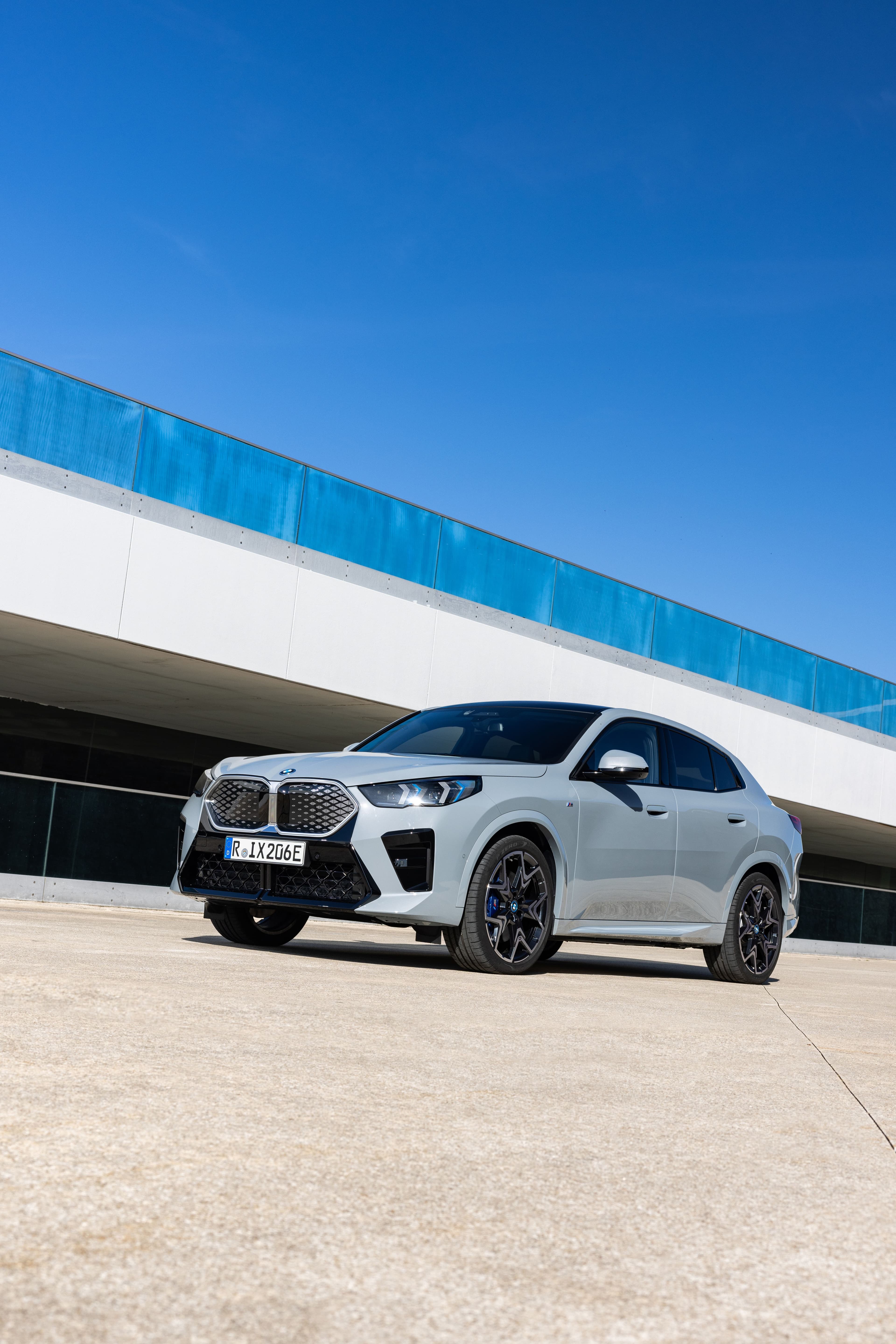 Silver BMW X6 parked outdoors with a blue sky overhead.