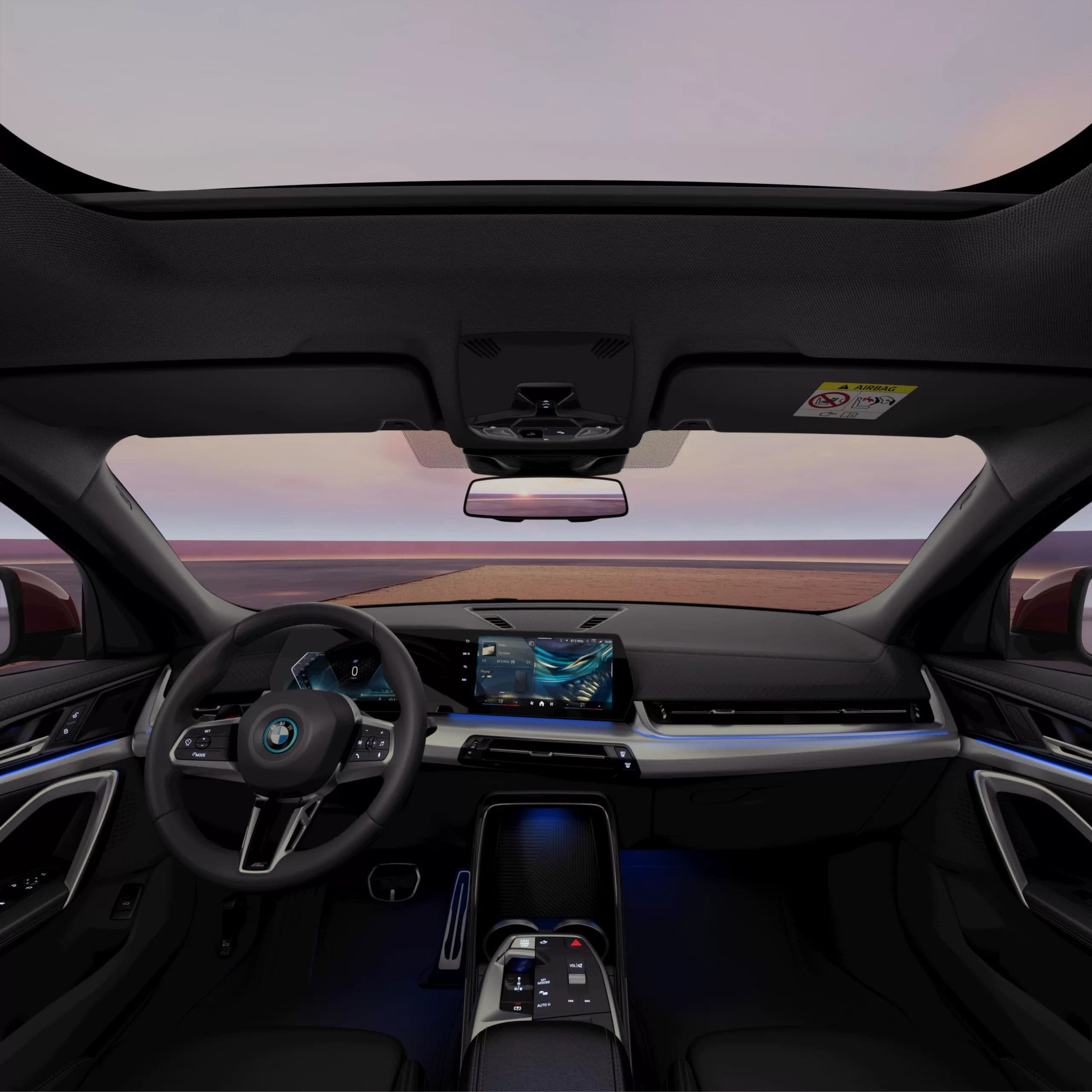 Interior view of a modern car's dashboard, steering wheel, and illuminated screen.